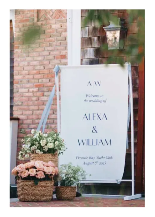Wedding welcome sign for Alexa and William at Peconic Bay Yacht Club with floral baskets beside it.